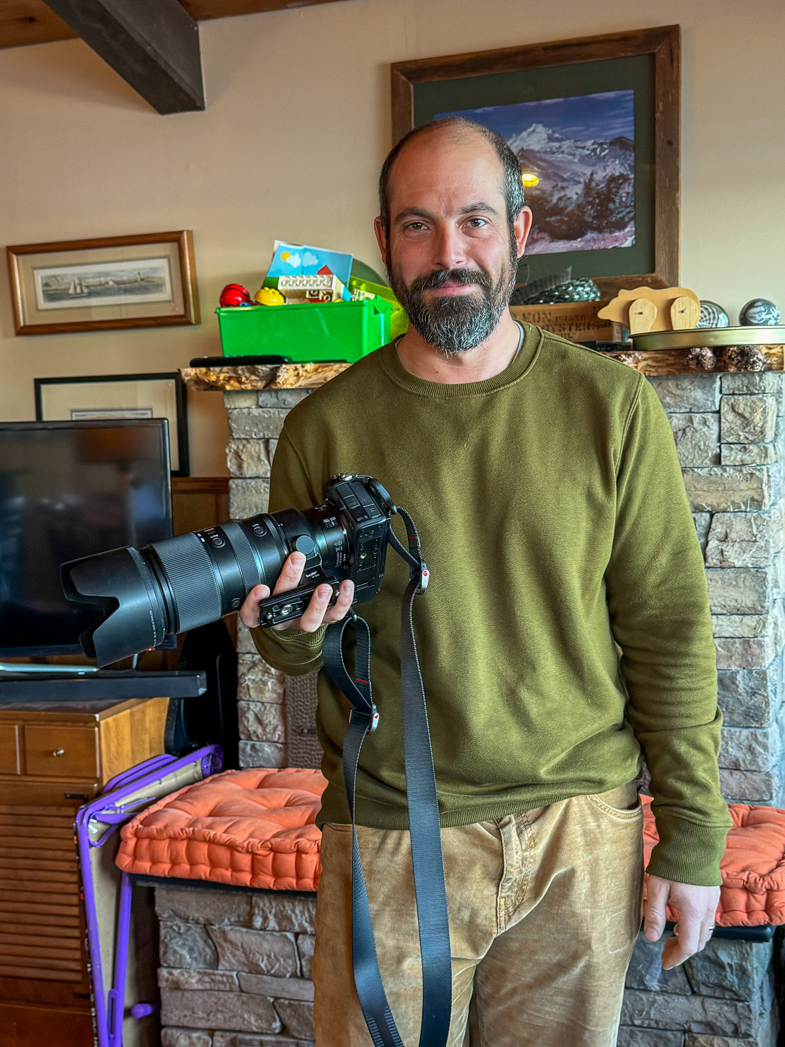 A photograph of a man, Matt Kurjanowicz, holding a camera.